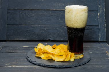 Bir bardak koyu bira ve cips. Kayrak bir tepsi üzerinde hizmet. Köpük bira.
