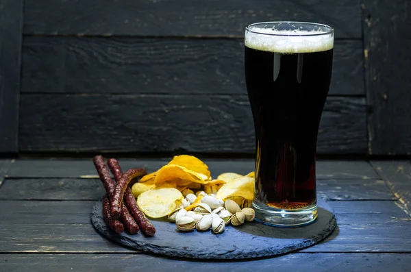 Dark beer with foam. A variety of snacks for beer. Beer composition.
