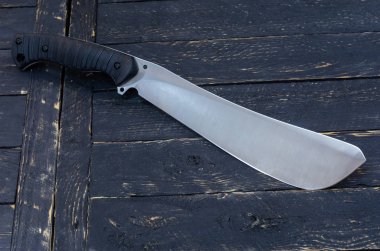 Büyük av bıçağı. Palayı yalıtmak. Koyu ahşap arka plan.