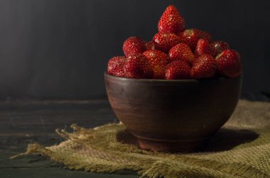 Çilek çanak çömlek içinde. Kil plaka ve çuval bezi. Önden görünüm.