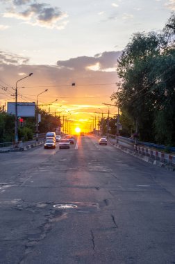 Günbatımı yolun üzerinde. Güneşe doğru yol. Olağandışı gökyüzü. Yol ve arabalar.