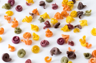 Doku derin gölgeler. Beyaz bir arka plan üzerinde renkli makarna. İtalyan mutfağı.