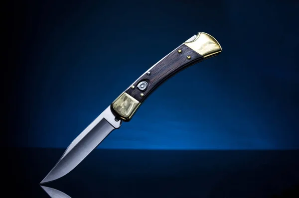 Folding knife hunter. Pocket knife hunter. Blue background.