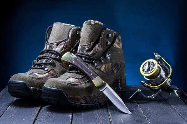 Botas de caza, cuchillo y carrete de pesca. Zapatos y cazador de herramientas . — Foto de Stock