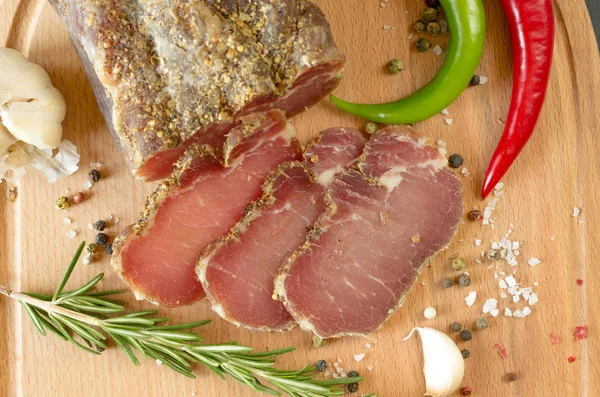 Gedroogd rundvlees. Gesneden rundvlees schokkerig. Vlees op een houten plank. — Stockfoto