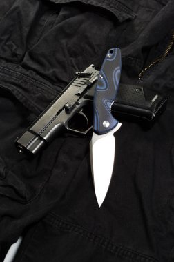 Silahın üzerinde çakı. Siyah pantolon üzerinde bıçak ve tabanca.