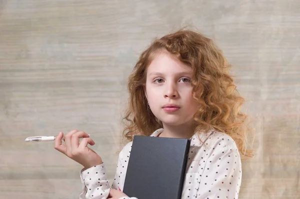 A teenager holds a pen and notebook. Girl with a notebook and pen.