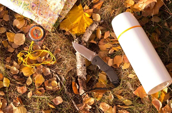 Trockene Herbstzweige und gelbe Blätter. Messer, Thermoskanne und Karte. — Stockfoto