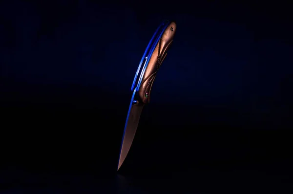 Cuchillo negro sobre fondo negro. Luz multicolor en el cuchillo . — Foto de Stock