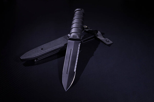Black knife with a plastic sheath. Army knife. A sharp knife with a saw.