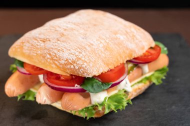 Sosisli ve sebzeli beyaz çörek. Sosisli sandviç ve abur cubur. Üst.