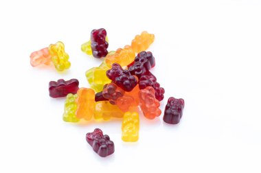 Ayı şeklinde jelibonlar. Beyaz arka planda tatlı çiğneyen bebek.