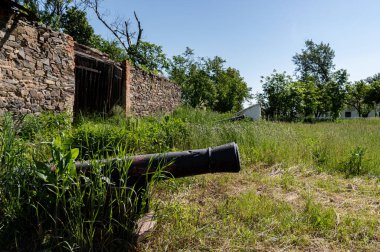 Birinci Dünya Savaşı 'nın silahı. Binanın yakınında bir silah var. Bir ahır ve bir top. Gün ışığı.