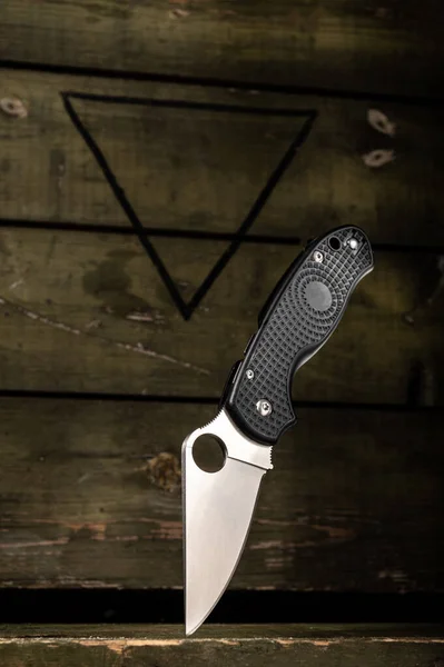 Folding knife on the background of a military box. Unique knife. Vertical frame.