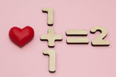 Aşk matematik. Bir artı bir eşittir iki. Pembe bir arka plan.