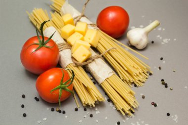 Gri bir arka plan üzerinde makarna yemek pişirmek için malzemeler bir dizi