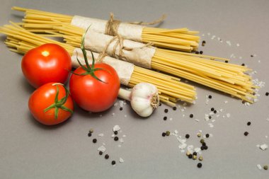 İtalyan malzemeler makarna ve gri arka plan üzerinde sebze (domates, makarna, sarımsak, biber, peynir, baharat). Vejetaryen Gıda, sağlık veya pişirme kavramı.