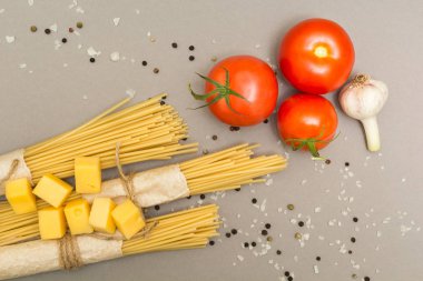 Makarna hazırlanması için malzemeler. Spagetti, peynir, domates, sarımsak, gri bir arka plan üzerinde. Üstten Görünüm.