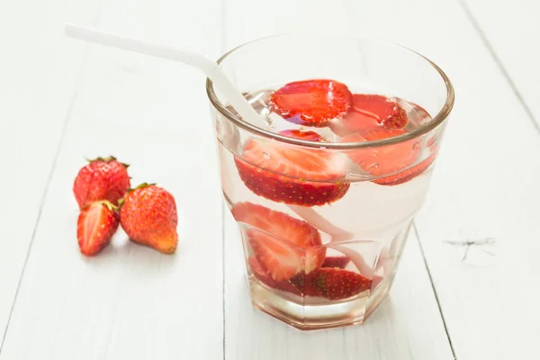 Fruchtwasser in einem Glas auf einem weißen Tisch. Bio-Erdbeere. — Stockfoto