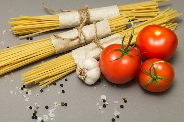 Gri bir arka plan üzerinde klasik bir makarna tarifi. Makarna ve sebzeler.