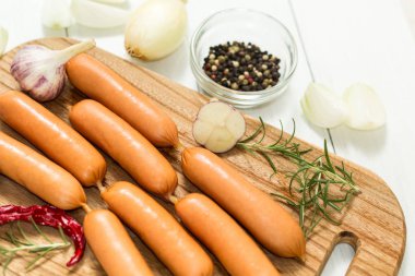 Bir kesme tahtası üzerinde baharatlar ile çiğ sosis.