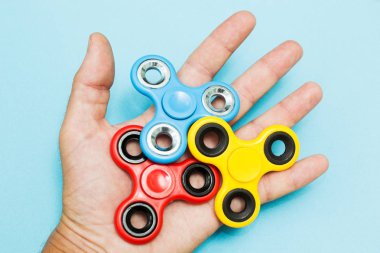 Birçok popüler topluca spinner oyuncak mavi arka plan üzerinde tutan el