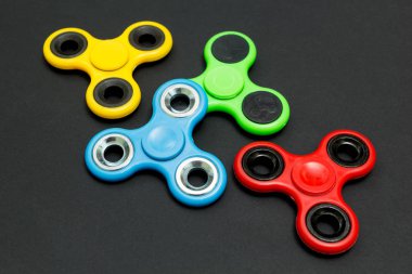 Çok renkli kıpır parmak spinner stres siyah arka plan üzerine.