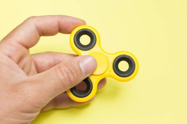 Popüler topluca spinner oyuncak sarı arka plan üzerinde tutan el