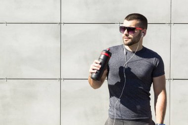 Genç bir kaslı adam su içer. Spor ve fitness kavramı