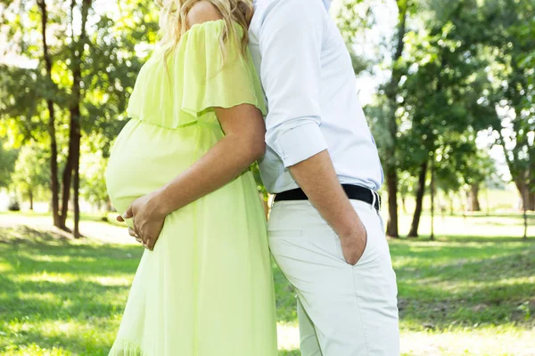 男と妊娠中の女性は公園 鯉の計画の背景に背を向けて立っています — ストック写真