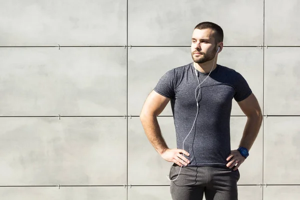 Young muscular man after fitness and listen to music in headphones. The concept of sport and fitness