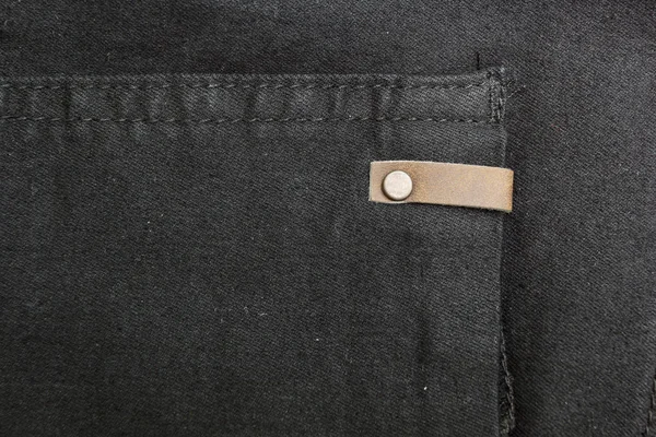 Background of black denim with copper elements and seams. Space for text.