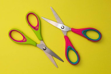 Sarı bir arka plan üzerinde izole kırmızı ve yeşil bebek makas.