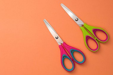 Turuncu zemin üzerine izole kırmızı ve yeşil bebek makas.