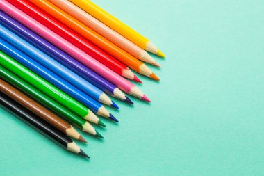 Yeşil bir arka plan üzerinde renkli kalemler kümesi. Okul için hazırlık.