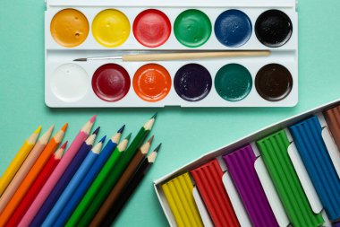 A yaratıcılık ve çizim için ayarla: suluboya, hamuru ve yeşil bir arka plan üzerinde renkli kalemler. Üstten Görünüm.