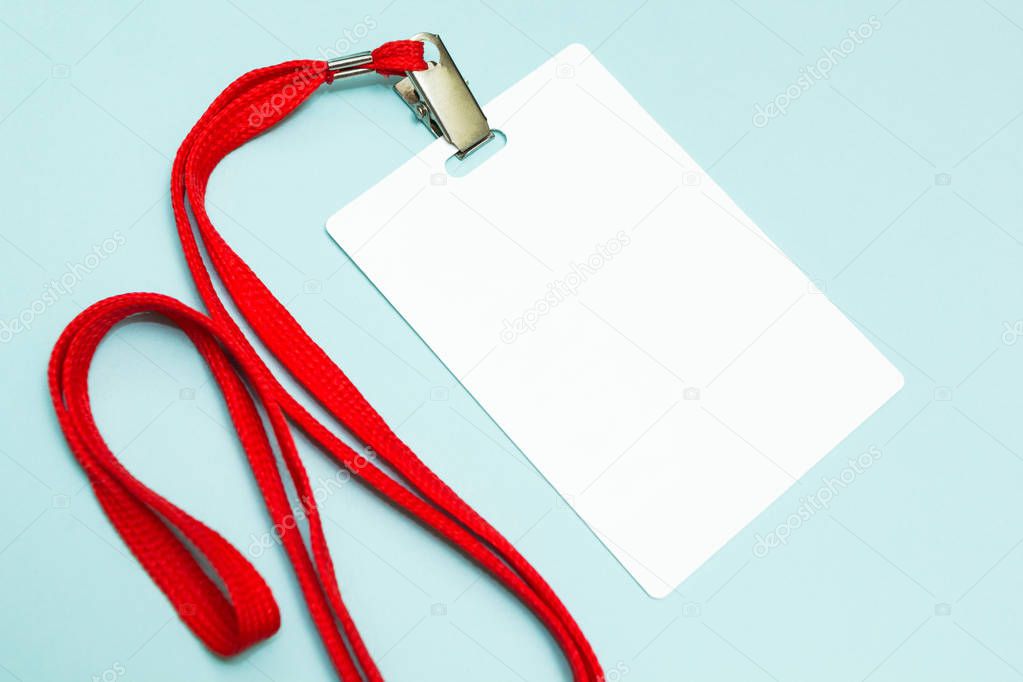 Blank badge mockup isolated on blue. Plain empty name tag with red string.