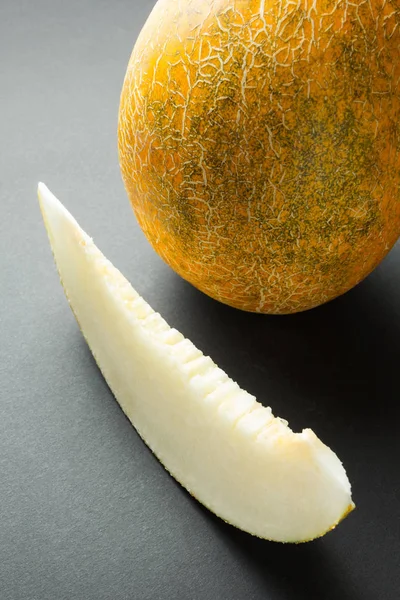 Fresh organic melons sliced on black background, vertical.