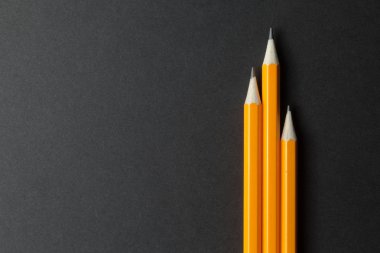 Siyah kağıt, boş alanı üzerinde üç sarı kalemler.