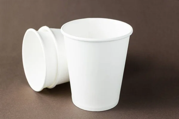 White paper cups mockup on brown background, space for text or l