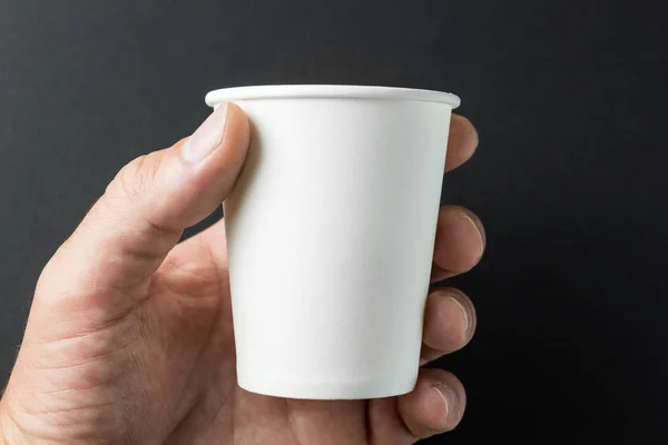 Mano sosteniendo una taza de papel blanco para té caliente y café en negro b — Foto de Stock