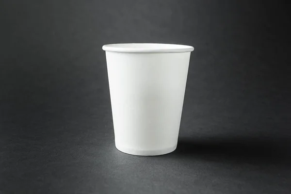 Empty white paper cup on the black background, mockup.