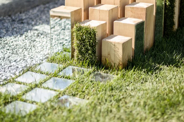 Wooden sculpture with mirrors on the background of grass. Modern