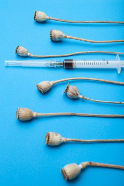 Eroin şırınga ve afyon mavi bir arka plan üzerinde. Yasadışı uyuşturucu