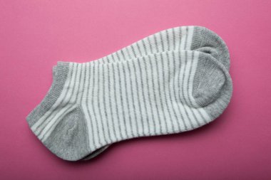 Pembe bir arka plan üzerinde şeritler halinde gri kadın çorapları.