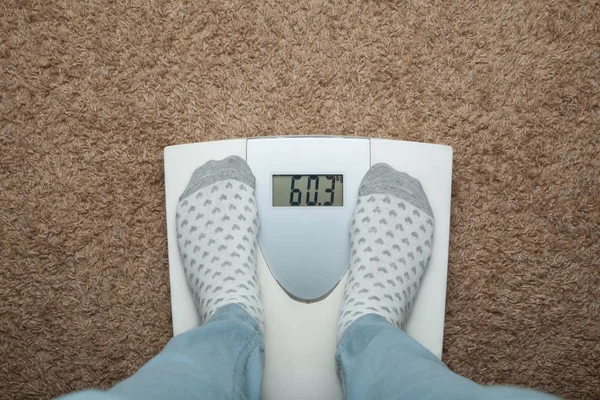 Female feet in socks on electronic scales. Excess weight and die
