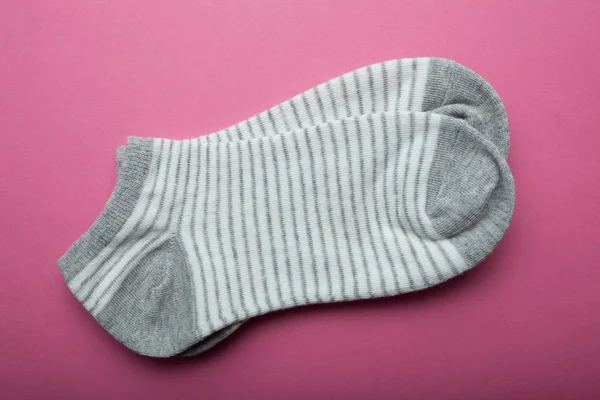 Csíkok a rózsaszín háttér-szürke női zokni. — Stock Fotó