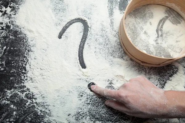 En kvinnas hand ritar ett frågetecken på mjöl. Sikten för mjöl en — Stockfoto