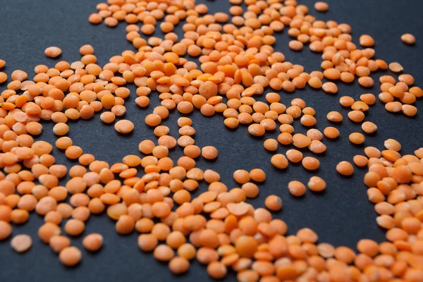 Grani d'arancia biologici lenticchie su fondo nero . — Foto Stock