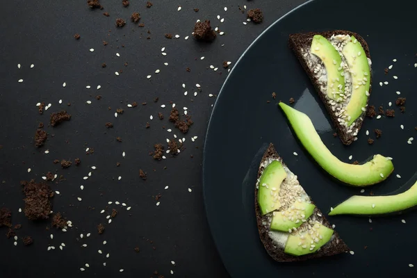 Avokado sandviç taze dilimlenmiş avoca yapılan koyu siyah ekmek üzerinde — Stok fotoğraf